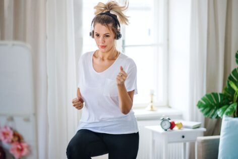 Woman does marching exercises with headphones on